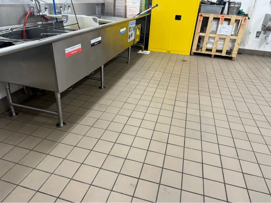 Commercial kitchen tile floor and three-compartment sink after steam cleaning